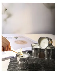 Primer plano encendiendo una vela de soja y citronela en un cubo de metal pequeño.