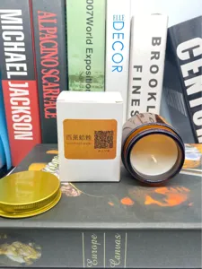 Primer plano de una vela aromática de soja en tarro de cristal marrón con su caja