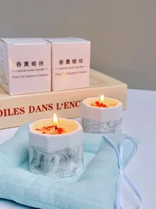 Macro shot of handmade soy wax scented candle in marble gypsum cup with white gift boxes
