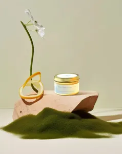 Aromatherapy soy candle in gold tin on decorative wooden stand with white flower