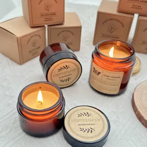 Warm soy wax scented candles in amber glass jars with vintage labels on white fabric backdrop.