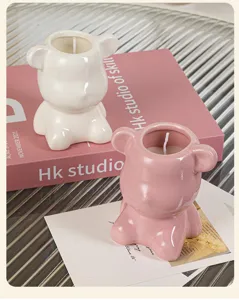 Detailed view of two cute bear-shaped ceramic scented candles on a decorative pink book.