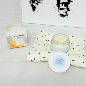 Handgefertigte Duftkerze aus Sojawachs im Glas auf einem weißen Polka-Dot-Kissen.