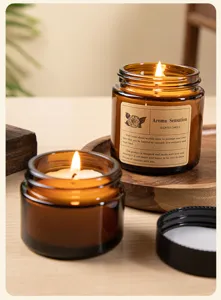 Detailed view of burning scented candles in amber glass jars on a rustic wooden tray