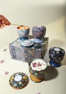 Dettaglio di candele profumate in stile calice con fiori secchi e confezione regalo.