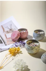 Close-up of decorative scented soy wax candles with dried flower petals in metal tins