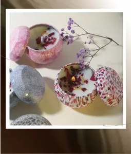 Close-up of scented soy wax candles with dried flowers in patterned tins