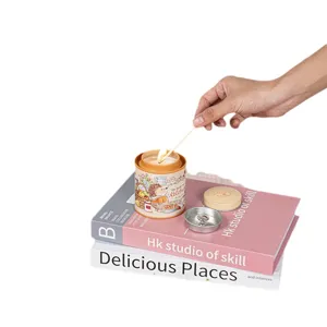 Aromatic scented candle in a cute hedgehog tin being lit by hand on decorative books