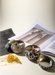 Lifestyle detail of leopard print tin soy wax candles featuring dried rose petals inside