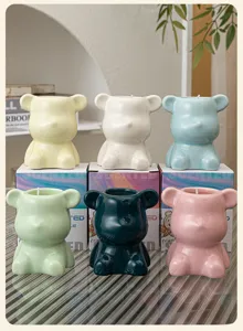 Detail view of six colorful bear-shaped ceramic soy wax candles with packaging boxes