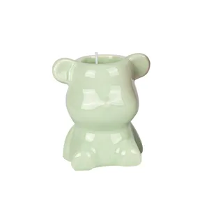 Cute light green ceramic bear shaped soy wax scented candle on white background.