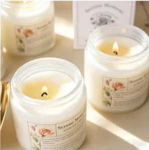 Gros plan d'une bougie parfumée haut de gamme en verre blanc avec motif floral