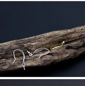 Detail view of S925 sterling silver and gold-plated pearl ear hook findings on wood