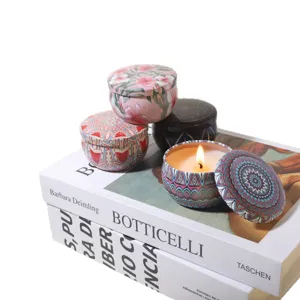 Velas perfumadas de cera vegetal en latas de flores decorativas sobre elegantes libros de arte