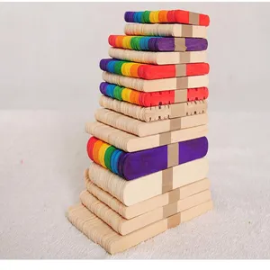 Macro view of stacked natural and rainbow-colored wooden popsicle sticks for DIY crafts.