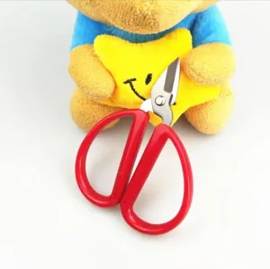 Close-up of red handled handicraft scissors held by a plush toy for DIY craft projects