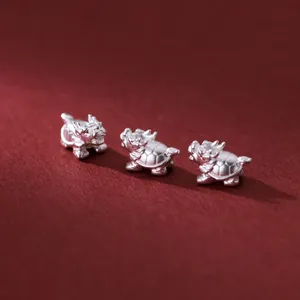 Three 999 pure silver dragon turtle charms for DIY bracelet jewelry on red background