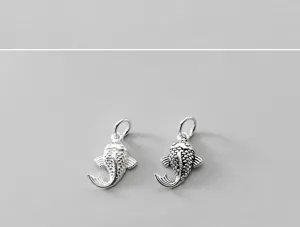 Close-up of aged S925 sterling silver fish pendants with intricate scale textures.