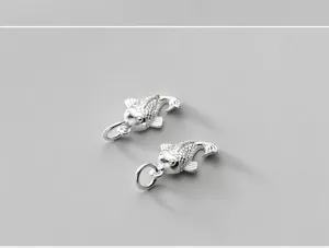 Close-up detail of two vintage S925 sterling silver whale charms with intricate scale textures