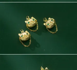 Détail macro de mignons pendentifs chat en argent S925 doré avec lunettes et yeux verts.