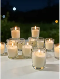 Close-up of burning ivory white candles in clear glass cups for romantic dinner decor