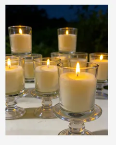 Macro view of multiple lit ivory white unscented candles in transparent glass cups