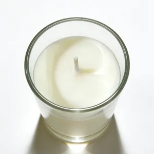 Top-down view of ivory unscented candle in clear glass cup for romantic dinners