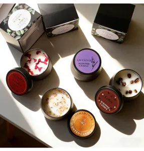Vue rapprochée de bougies parfumées au soja dans des boîtes noires avec fleurs et grains