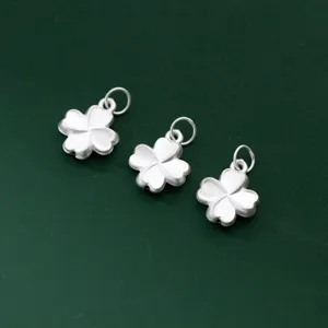 Three matte S925 silver four-leaf flower pendants on dark green textured background