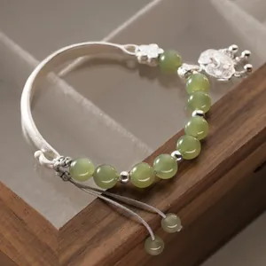 Dettaglio del bracciale in argento 999 con perle di giada verde e ciondolo lucchetto della pace