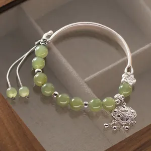 Dettaglio di un bracciale in argento 999 con perle di giada verde e ciondolo portafortuna Fu.