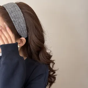 Gros plan sur un bandeau large en tricot gris avec motif torsadé sur cheveux bruns