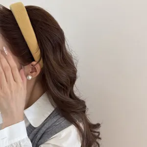 Gros plan d'un serre-tête en laine jaune moutarde porté par un mannequin aux longs cheveux