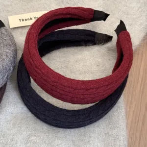 Gros plan sur la texture en maille torsadée des serre-têtes larges bordeaux et noirs.