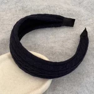 Gros plan d'un serre-tête large en maille noire avec texture laineuse douce.