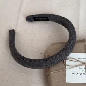 Gros plan d'un serre-tête en laine grise montrant la texture du tricot et l'étiquette.