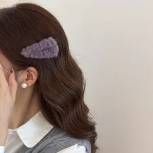 Vista detallada de una pinza para el pelo de felpa morada en cabello largo ondulado