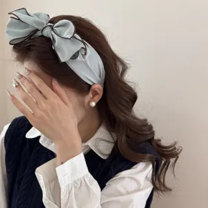 Vista dettagliata della fascia per capelli azzurra con fiocco a strati su modella