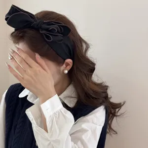 Vista laterale di un cerchietto vintage nero con fiocco 3D indossato da una modella