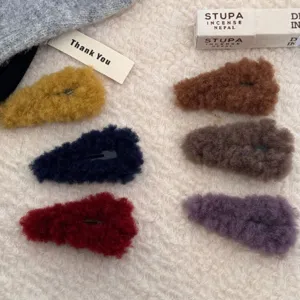 Primer plano de seis pinzas para el cabello de felpa en varios tonos otoñales e invernales.