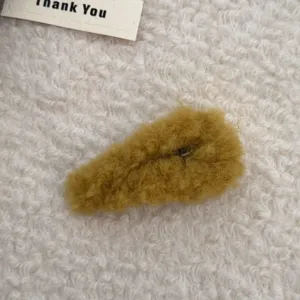Primer plano de una bonita pinza para el pelo de felpa amarillo mostaza suave de invierno