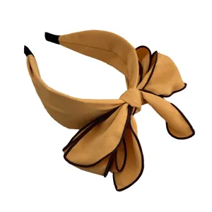 Cerchietto largo giallo elegante con grande fiocco 3D e bordo scuro a contrasto.