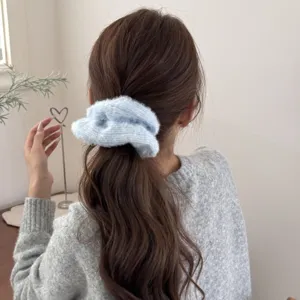 Nahaufnahme eines weichen hellblauen Strick-Scrunchies auf langem braunem gewelltem Haar