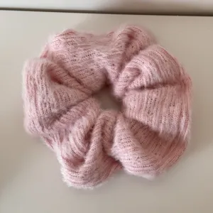 Nahaufnahme eines weichen, rosa flauschigen gestrickten Haargummis mit Wolltextur