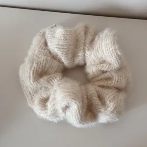 Makrodetail eines weichen cremefarbenen Strick-Haargummis mit einer flauschigen Wintertextur