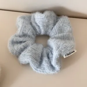 Nahaufnahme der Textur eines weichen, hellblauen, flauschigen Strick-Haargummis