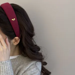 Detalle de una diadema de lana granate con lazo dorado llevada por un perfil