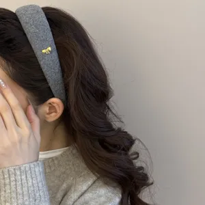 Detalle de una diadema de lana gris para invierno con un delicado adorno de lazo dorado en modelo.