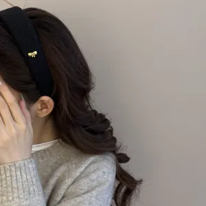 Primer plano detallado de una elegante diadema de lana negra con un pequeño lazo dorado chic