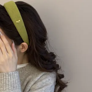Primer plano de una diadema de lana verde premium con un pequeño lazo dorado